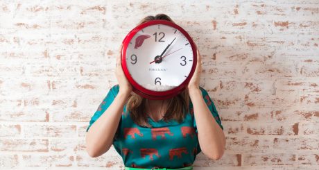 woman covering face using wall clock